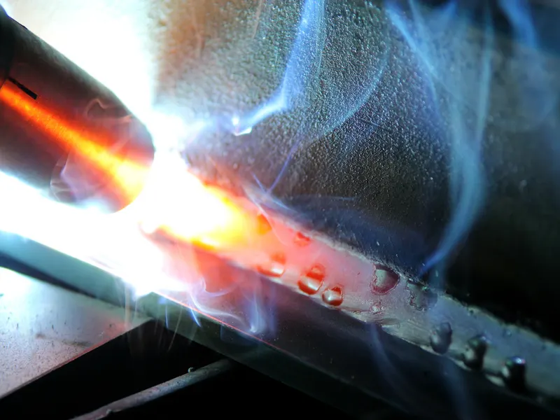 Gros plan d'un cordon de soudure en cours d'exécution, la torche fait fondre le métal en fusion orange